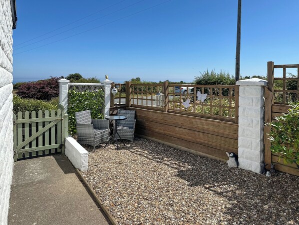 A patio area with a table and chairs, a wooden fence, and a view of the sea.