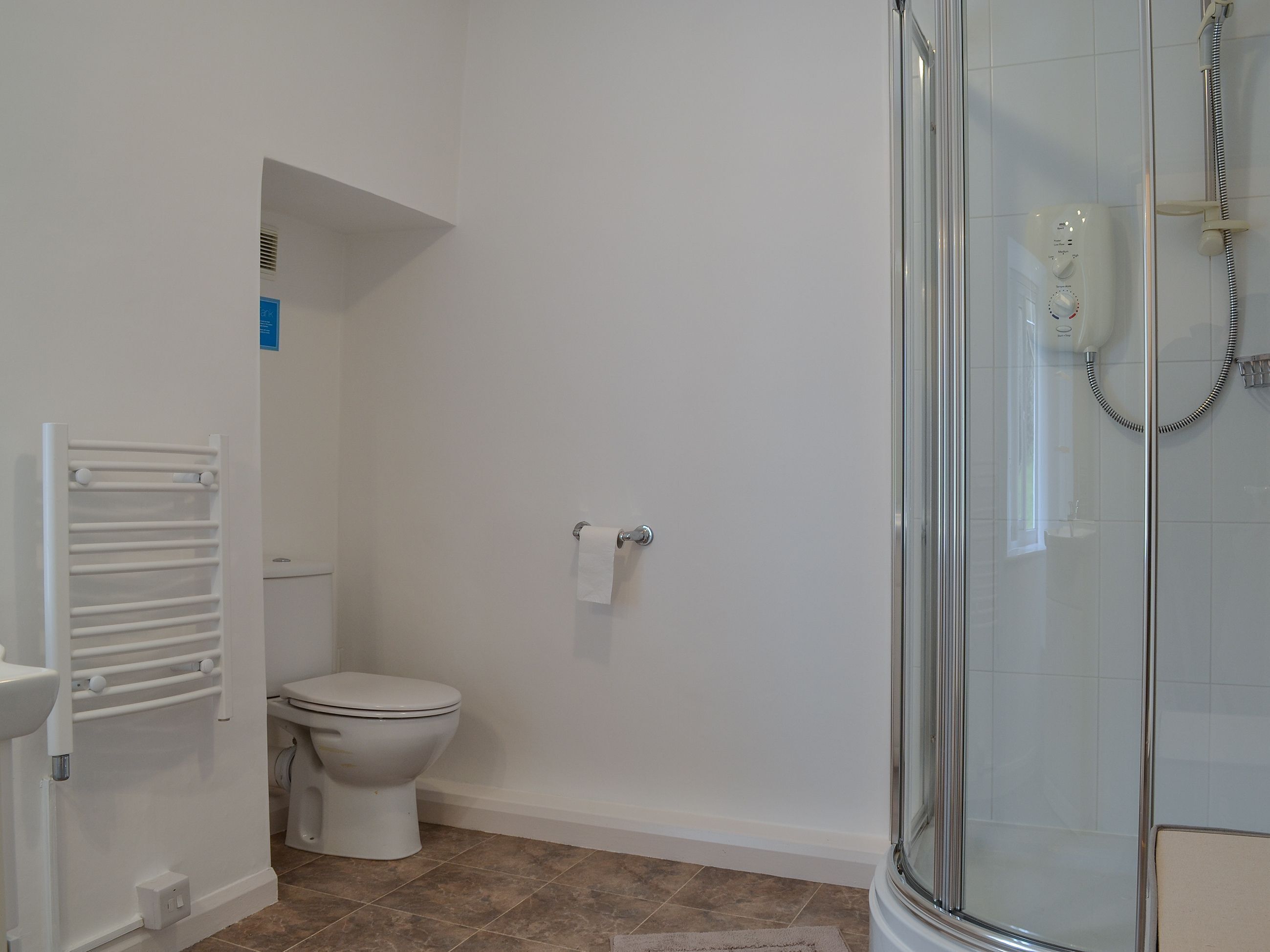 A bathroom with a toilet, a glass shower enclosure, and a towel rack.