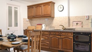 Una cocina con armarios de madera, un lavamanos, una estufa y una mesa de comedor lista para una comida.