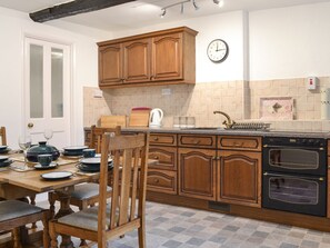 Une cuisine avec des meubles de rangement en bois, un évier, une cuisinière et une table à manger mise pour le repas.