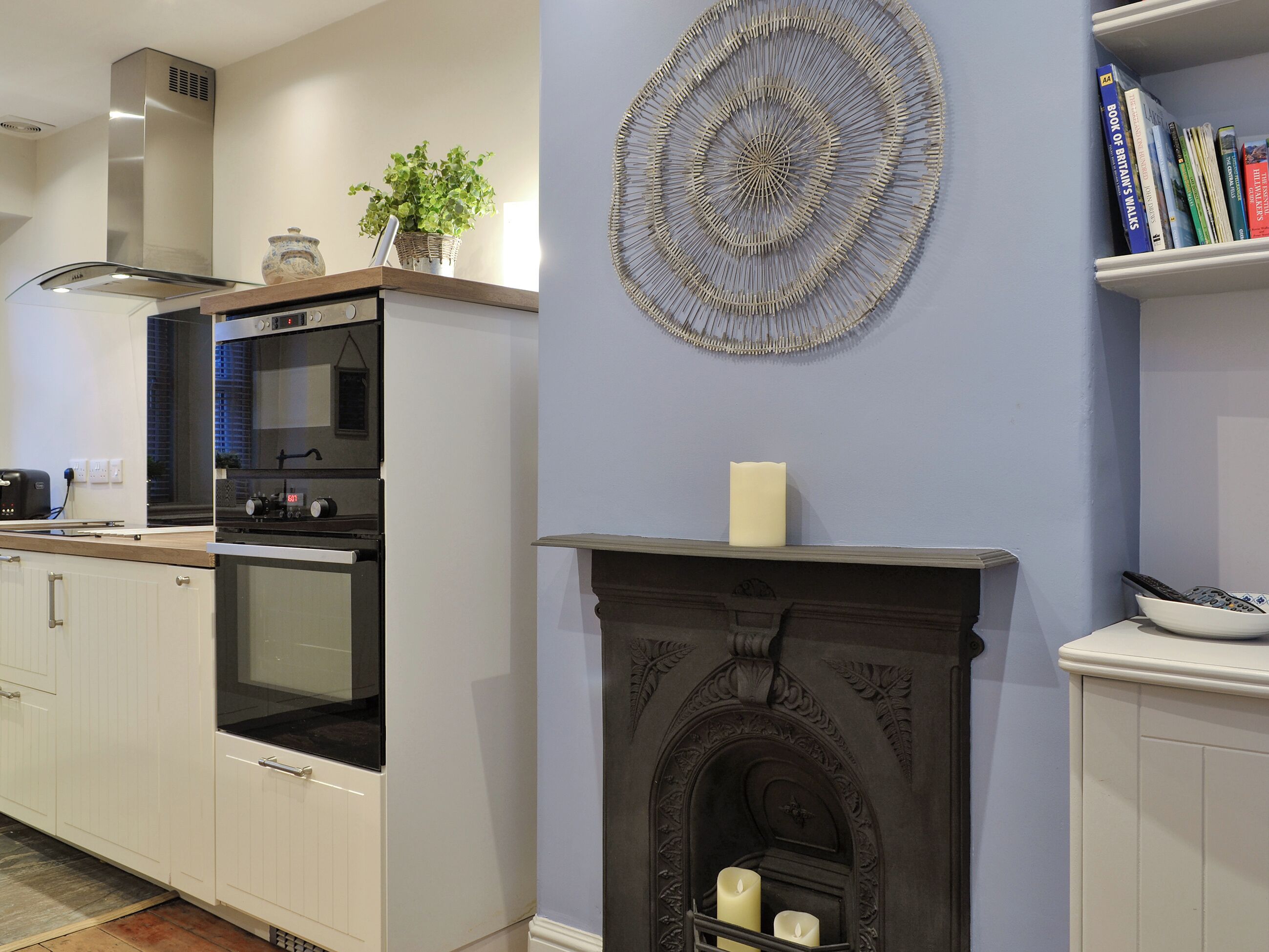 A modern kitchen with a built-in oven and microwave, a decorative wall piece, and a fireplace with a candle.