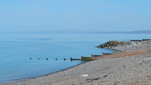 A rocky beach with a wooden jetty extending into calm waters.