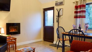 A cozy living room with a fireplace, a dining table with chairs, and a sofa.