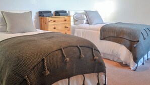 Une chambre avec deux lits, une commode en bois et une œuvre d’art murale.