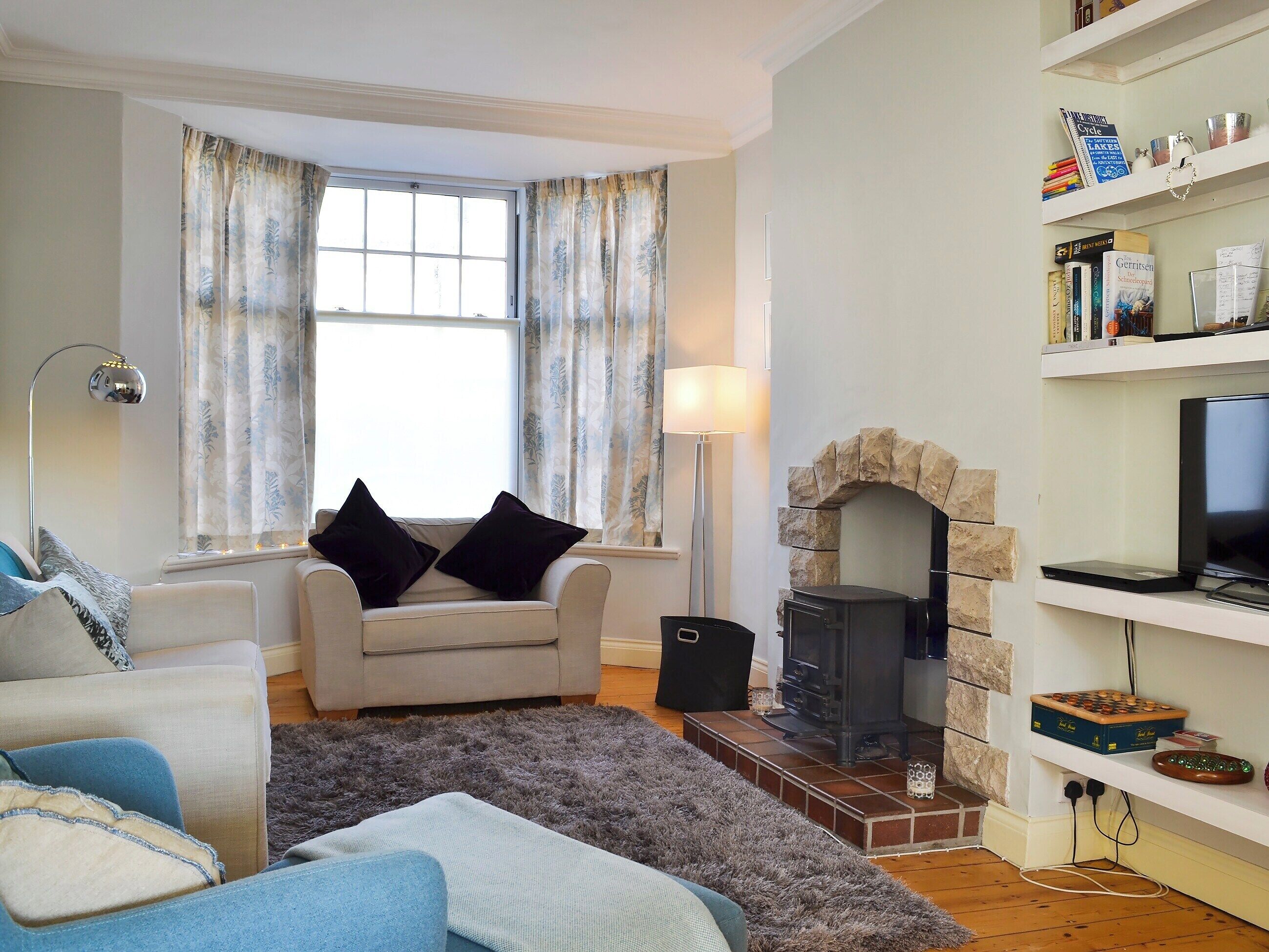 Una sala de estar con chimenea, un sofá, una silla, una lámpara y una estantería.