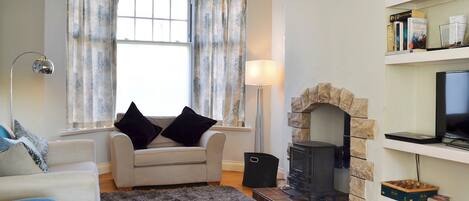 Una sala de estar con chimenea, un sofá, una silla, una lámpara y una estantería.
