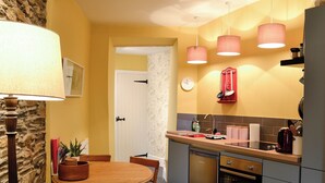 Cocina compacta con comedor, destacando una pared de piedra, una mesa de madera y un horno moderno.