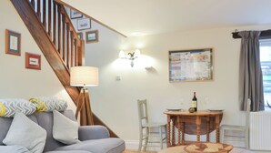Ein Wohnzimmer mit grauem Sofa, Holzesstisch und einer Treppe.