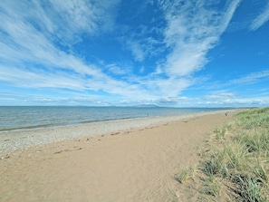 A beach with a clear sky and distant mountains.