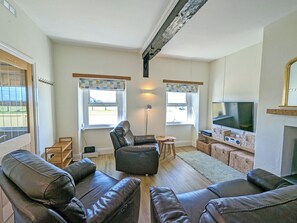 Een woonkamer met leren banken, een televisie en een open haard.