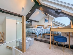 A bedroom with a skylight, a bed with patterned bedding, a bedside table, a chair, and a mirror.