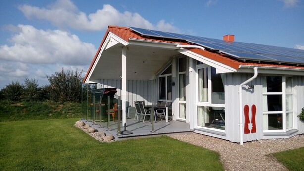 A house with a covered patio, solar panels, and a view of the surrounding landscape.