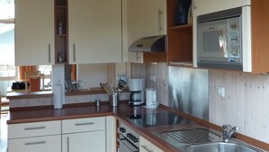 A modern kitchen with white cabinets, a stainless steel sink, and a built-in microwave.