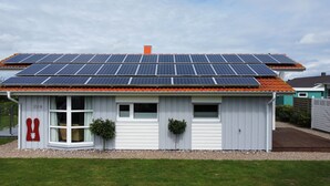 A house with solar panels on the roof and a small attached garage.