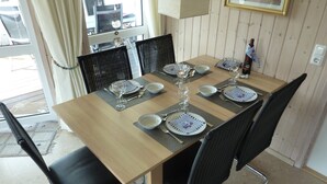 A dining table set with plates, bowls, cutlery, and a bottle of wine.