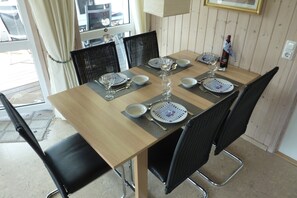 Enjoy meals and social gatherings in this inviting dining area with a table set for four, complete with place settings and a wine bottle.