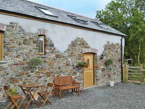 A stone building with a wooden door, a window, and a bench.