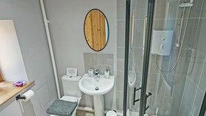 A modern bathroom with a toilet, sink, and glass-enclosed shower. - 2 bedroom accommodation in Derril, near Bude (Derril, near Bude)