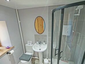 Une salle de bain moderne équipée de toilettes, d’un lavabo et d’une douche à parois de verre.