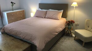 Ein Schlafzimmer mit Bett, Nachttisch, Stuhl, Kommode und Lampe.
