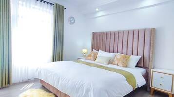 A modern bedroom with a large bed, a fluffy rug, a bedside table, and a nightstand.