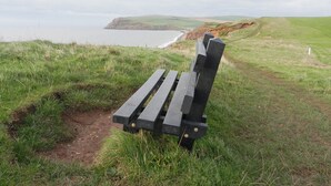 Un banc amb vista a un paisatge costaner i al mar, amb penya-segades.