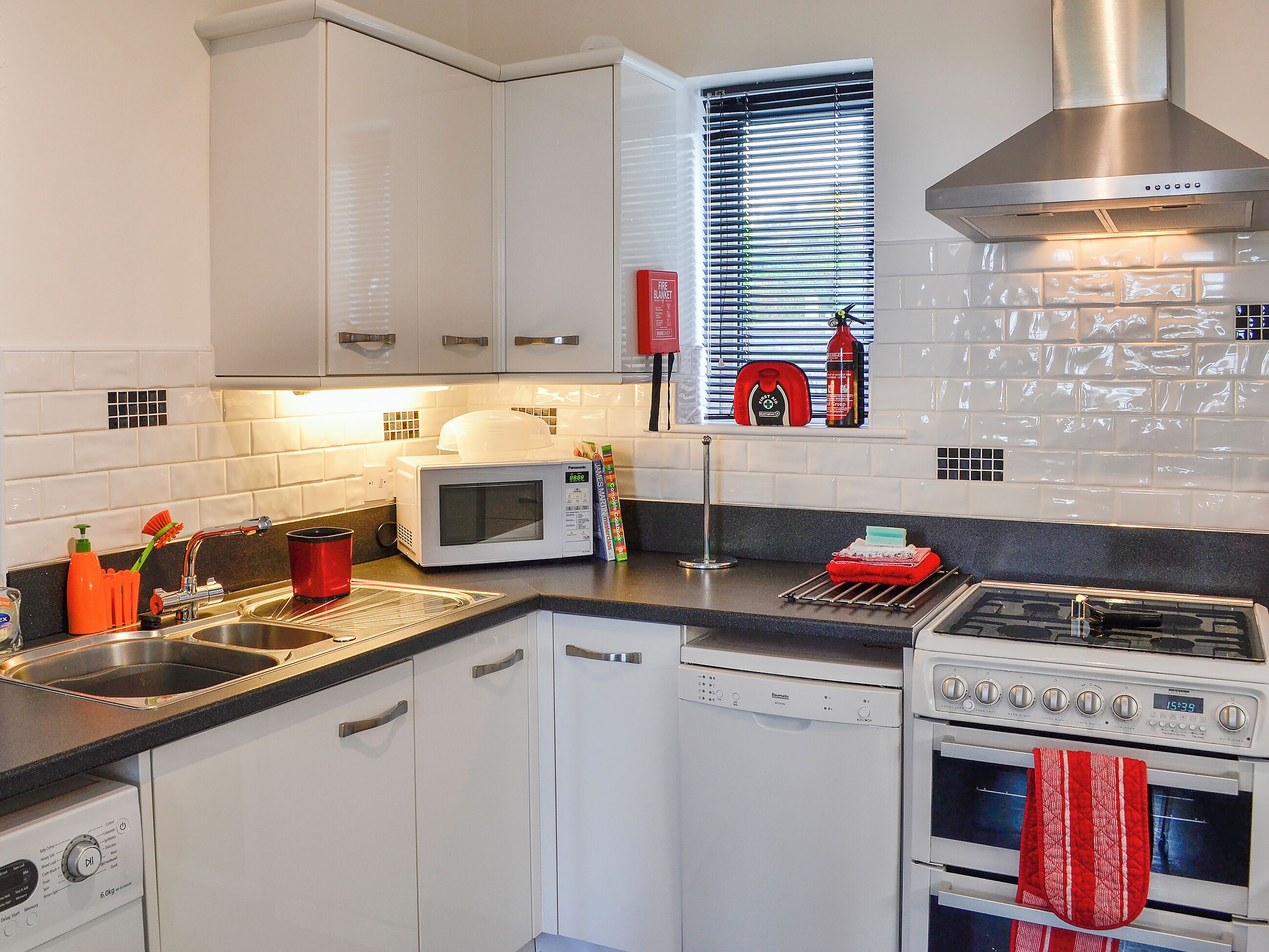 Una cocina moderna con armarios blancos, microondas, lavavajillas y estufa.