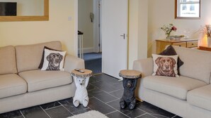 A living room with two sofas, each with a dog-themed pillow, a small bear statue, and a round wooden table. - 3 bedroom accommodation in Keswick (Keswick)
