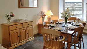 A dining area with a wooden table set for four, a wooden cabinet, a mirror, and a window with blinds. - 3 bedroom accommodation in Keswick (Keswick)