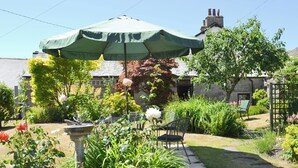 A garden with a stone fountain, a green umbrella, and two chairs. - A break at Bandrake Barn offers rest and relaxation. (Oxen Park, near Ulverston)