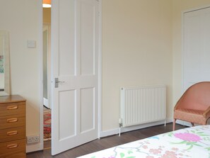 A bedroom with a wooden dresser, a radiator, and a chair. - 3 bedroom accommodation in Keir Mill, Thornhill (Keir Mill, Thornhill)