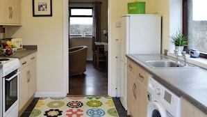Una cocina con lavadora, refrigerador y ventana con vista.