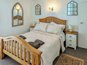 A neatly made bed with a wooden headboard, two bedside tables with lamps, and a patterned rug on the floor.