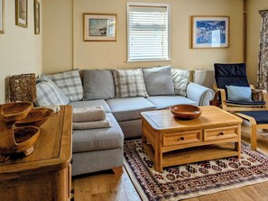 Un salon avec un canapé d’angle gris, une table basse en bois et un tapis à motifs.