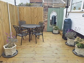 A wooden deck with a round table and chairs, surrounded by potted plants. - 2 bedroom accommodation in Wells-next-the-Sea (Wells-next-the-Sea)
