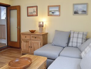 Un salon avec un meuble en bois, un canapé, un bol posé sur une table et deux tableaux encadrés accrochés au mur.