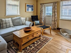 Un salon chaleureux avec un canapé, une table basse en bois, un fauteuil et un tapis à motifs.