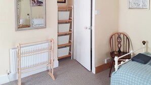 Ein Schlafzimmer mit einem hölzernen Babybett, einem weißen Heizkörper, einer weißen Tür und einem an der Wand befestigten Spiegel.