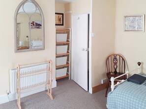 A bedroom with a wooden crib, a white radiator, a white door, and a wall-mounted mirror. - 2 bedroom accommodation in Wells-next-the-Sea (Wells-next-the-Sea)