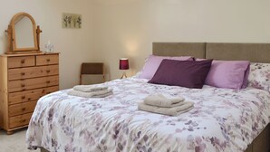 Un dormitorio con una cama, un aparador de madera, una silla y una lámpara.