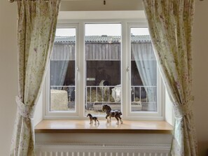 A window with a view of a rural area, a small shelf with figurines, and curtains. - 1 bedroom accommodation in Byley, near Middlewich (Byley, near Middlewich)