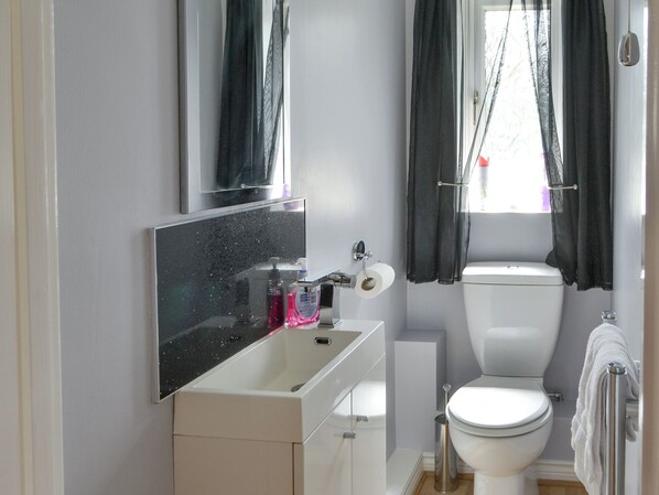 A modern bathroom with a white sink, mirror, and toilet.