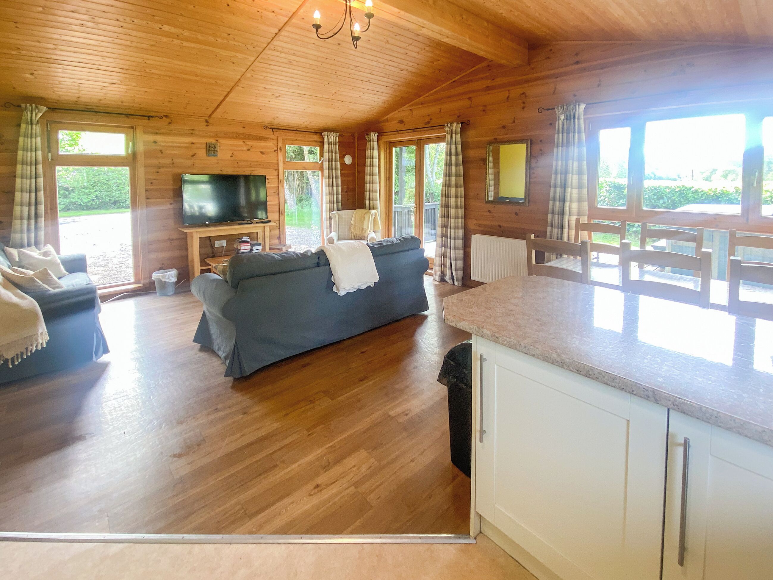 A wooden cabin interior with a sofa, TV, and dining area.