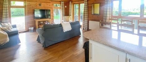 A wooden cabin interior with a sofa, TV, and dining area.