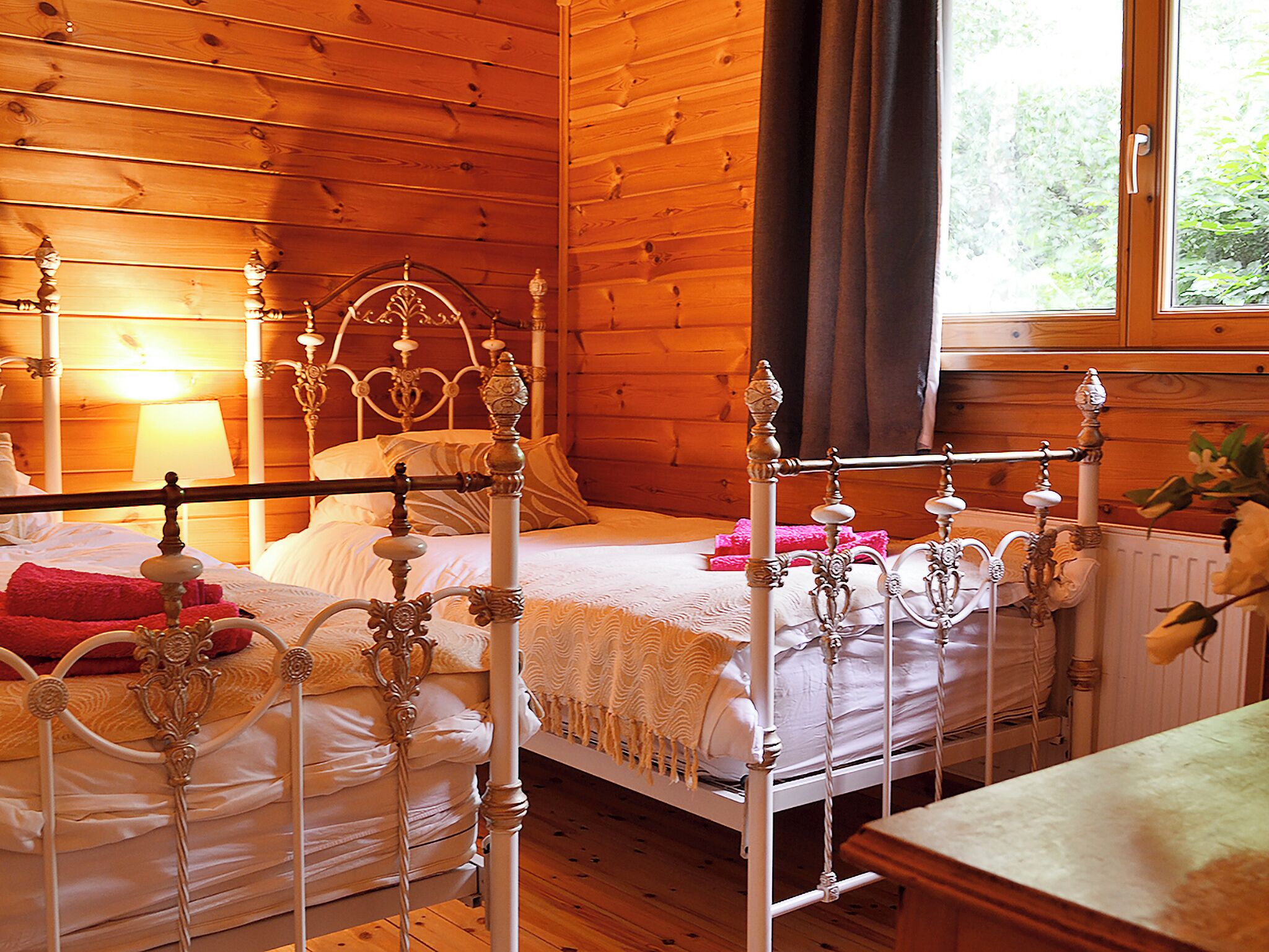 Une chambre à coucher dans une cabane en bois, avec un lit à baldaquin, une table de chevet et une fenêtre avec des rideaux.