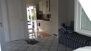 A compact kitchen with white cabinets, a small dining table, and a window with a view of the outside. - Villa Tre Palme Pagghiari (vulcano)