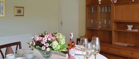 A dining table set with croissants, a floral arrangement, wine glasses, and a bottle of rosé wine.
