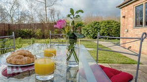 Ein Frühstückstisch mit Croissants, Orangensaft und einer Vase mit Blumen.