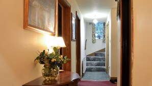 A hallway with a wooden table, a vase of flowers, a lamp, and a staircase. - 4 bedroom accommodation in Easingwold, near York (Easingwold, near York)