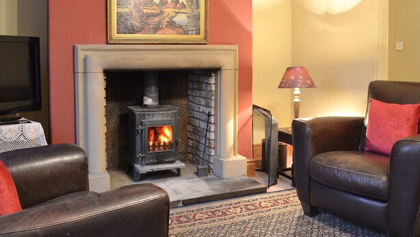 A living room with a fireplace, a painting above it, and two leather chairs. - 4 bedroom accommodation in Easingwold, near York (Easingwold, near York)